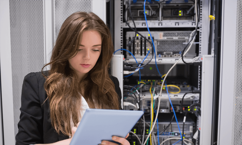 A person using a tablet in front of a server.