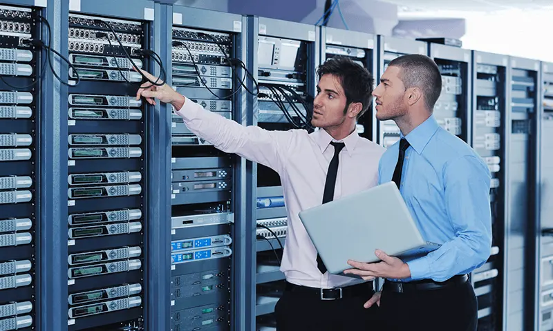 A pair of IT specialists inspecting stacks of servers together.